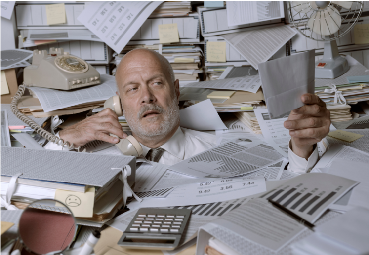 Hombre exhusto viendo facturas físicas por no usar Sistema FEL